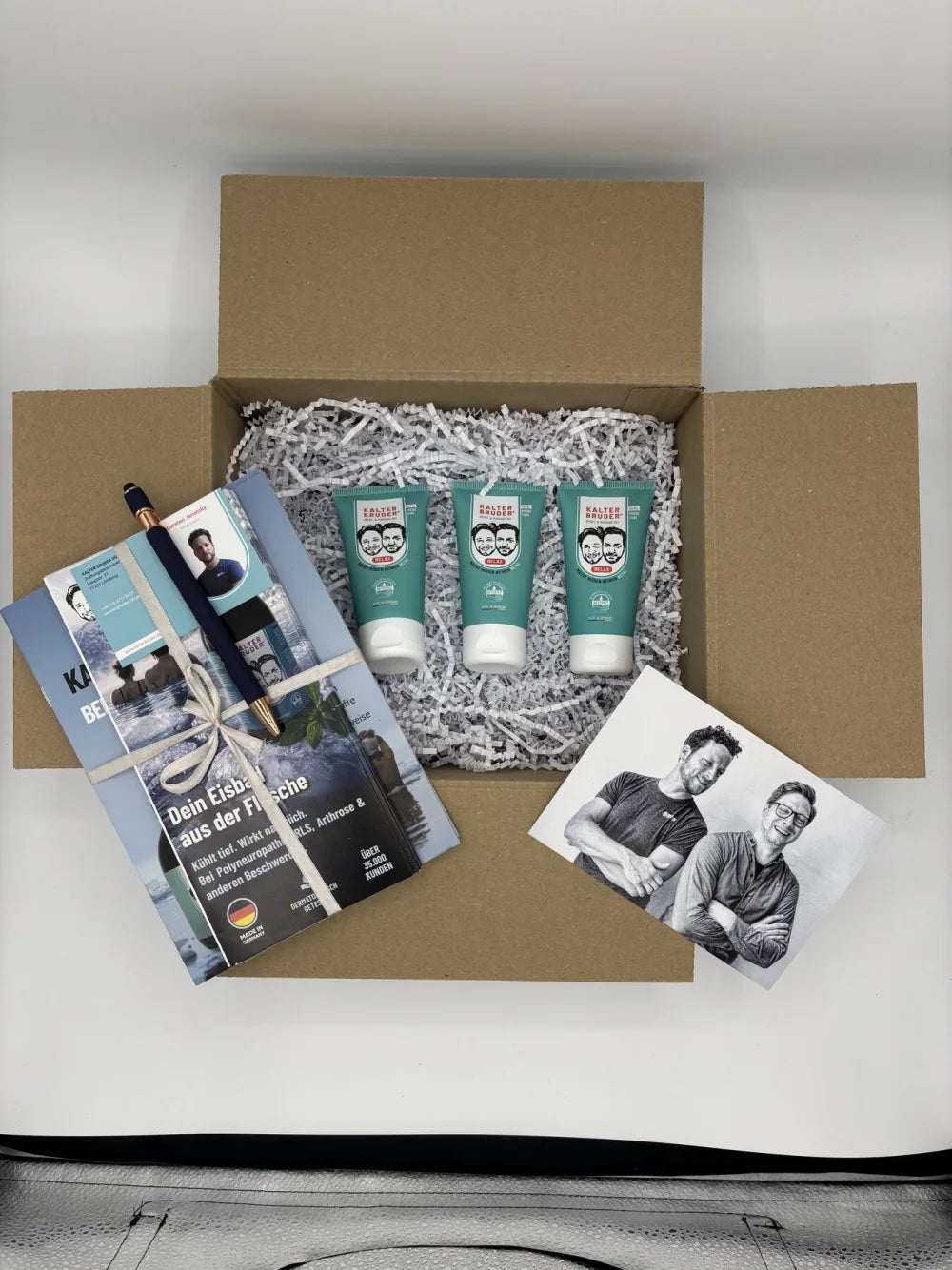 Geöffnetes Kalter-Bruder-Praxistestpaket mit drei 50-ml-Tuben, Broschüren, Anschreiben und Beigaben